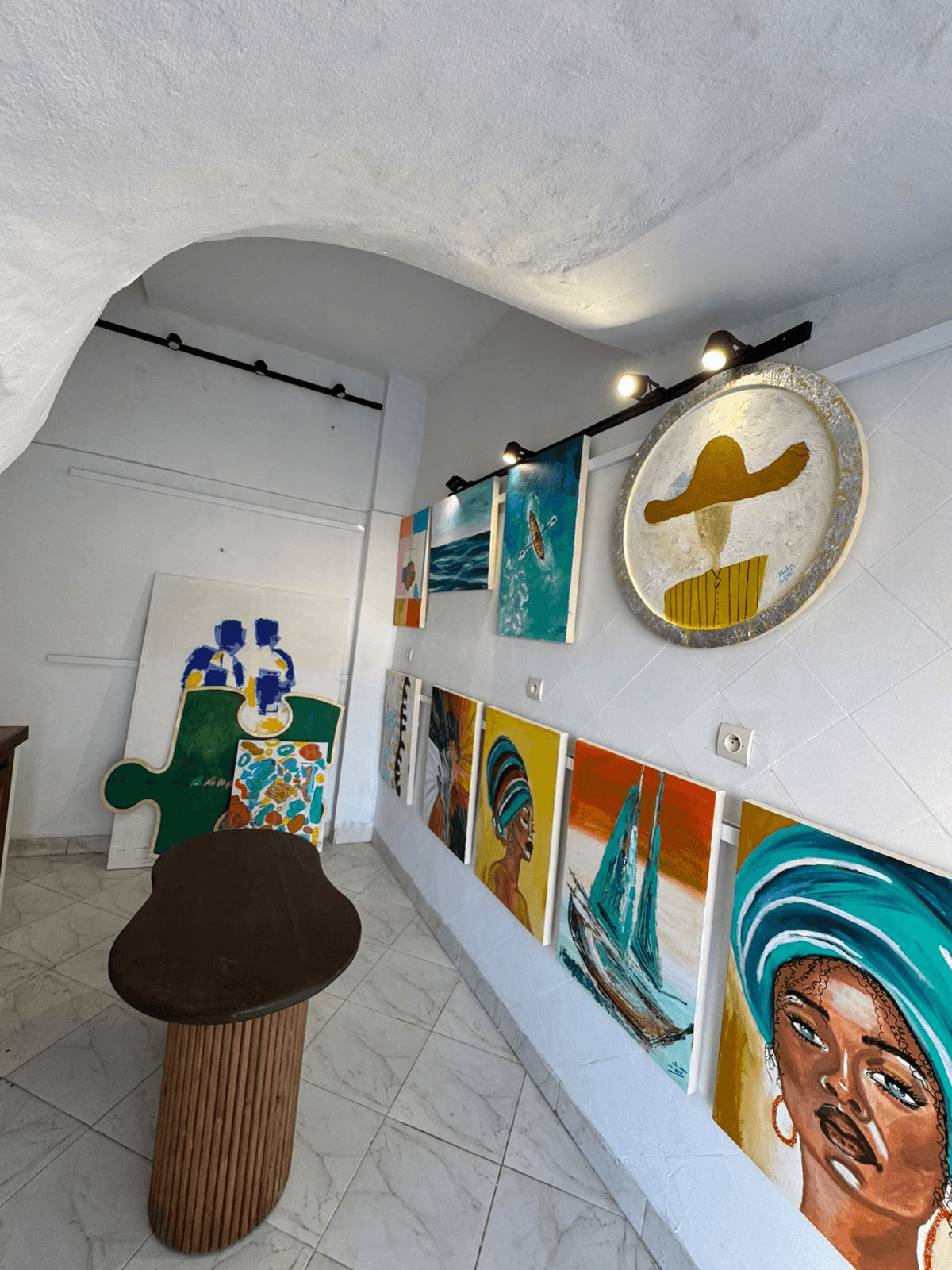 Colorful paintings and a wooden table inside the studio